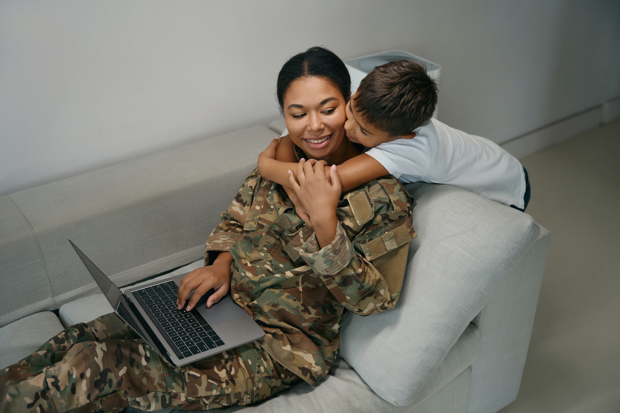 Military woman is located with a laptop on the sofa USA