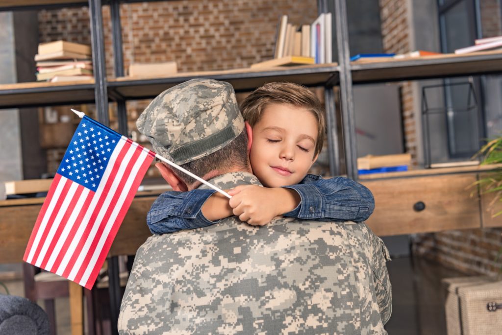 military father and son with usa flag embracing